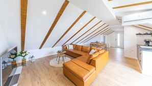 A modern living room with a large sectional sofa, wooden beams on the ceiling, and a kitchen area visible in the background. - Beautiful apartment in Kastel Novi (Kastel Novi)