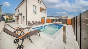 A modern building with a swimming pool, lounge chairs, and a view of the surrounding area. - Beautiful apartment in Kastel Novi (Kastel Novi)