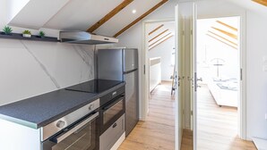 A modern kitchen with a black countertop, stainless steel appliances, and a wooden ceiling. - Beautiful apartment in Kastel Novi (Kastel Novi)