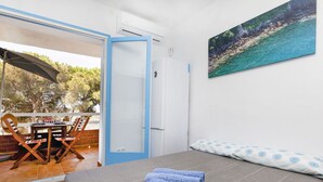 A bedroom with a bed, a painting, and a view of an outdoor patio with a table and chairs. - Cosy apartment for 4 people with A/C, pool, WIFI, TV and terrace (Tossa De Mar)