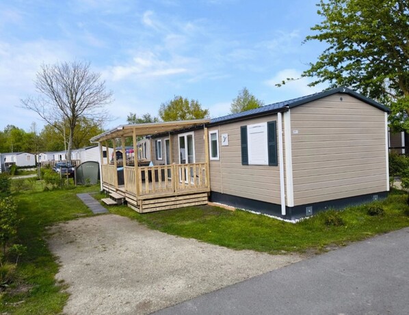 Une maison mobile dotée d’une terrasse en bois et d’un porche couvert.