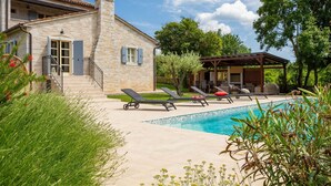 A stone house with a pool, outdoor seating, and a pergola.