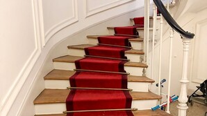 A staircase with red carpet runners and white balusters.