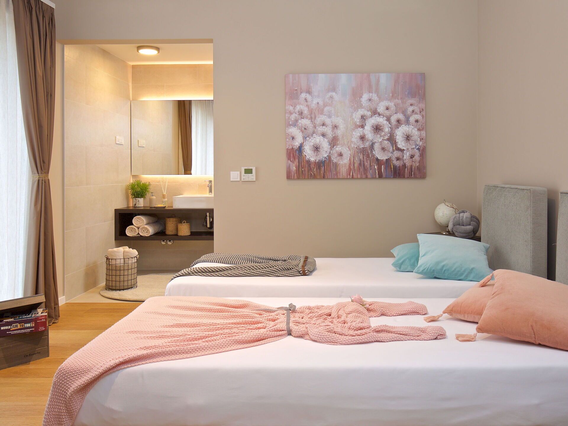 Habitación de hotel con dos camas, un espejo grande, un cuadro de flores y una planta pequeña en la tocador.