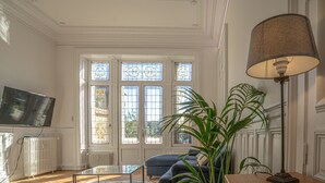 Una sala de estar con televisor, sofá, mesa de centro y lámpara.