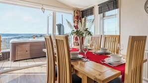 Un comedor con una mesa de madera dispuesta para cuatro personas, ventanas amplias y vistas al paisaje.