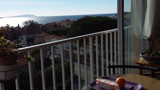 Ein Balkon mit Frühstückstisch, Blick auf das Meer und eine Stadtlandschaft im Hintergrund.