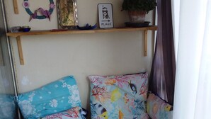 Eine gemütliche Ecke mit gepolsterten Sitzgelegenheiten, einem Regal mit Dekoration und einem Blumentopf.