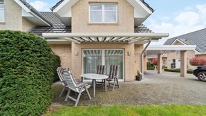 A house with a covered patio, a brick exterior, and a window. - 3 bedroom stunning home in Haren (Ems) (Haren (Ems))