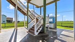 Ein überdachter Außenbereich mit einer Holztreppe, die zu einer Veranda führt.