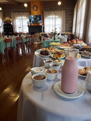 A buffet setup with various food items and a pink punch bowl on a table, surrounded by chairs and tables with checkered tablecloths.