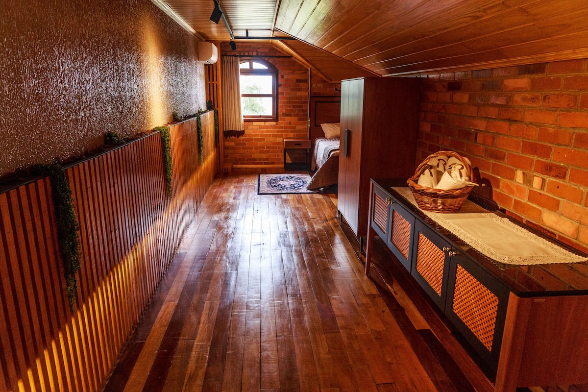A narrow, wooden-floored hallway with a bed and a basket on a bench.
