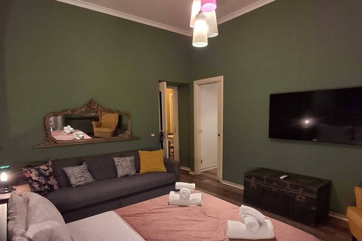 Un dormitorio con una cama grande, un sofá, un televisor y una maleta.