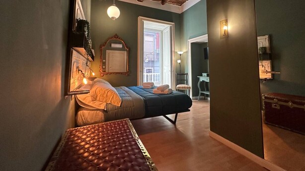 A bedroom with a bed, bedside table, and a view of the outside. - I Leoni di Rosaroll (Naples)