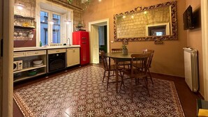 A kitchen with a red refrigerator, a dining table with chairs, and a patterned floor. - I Leoni di Rosaroll (Naples)
