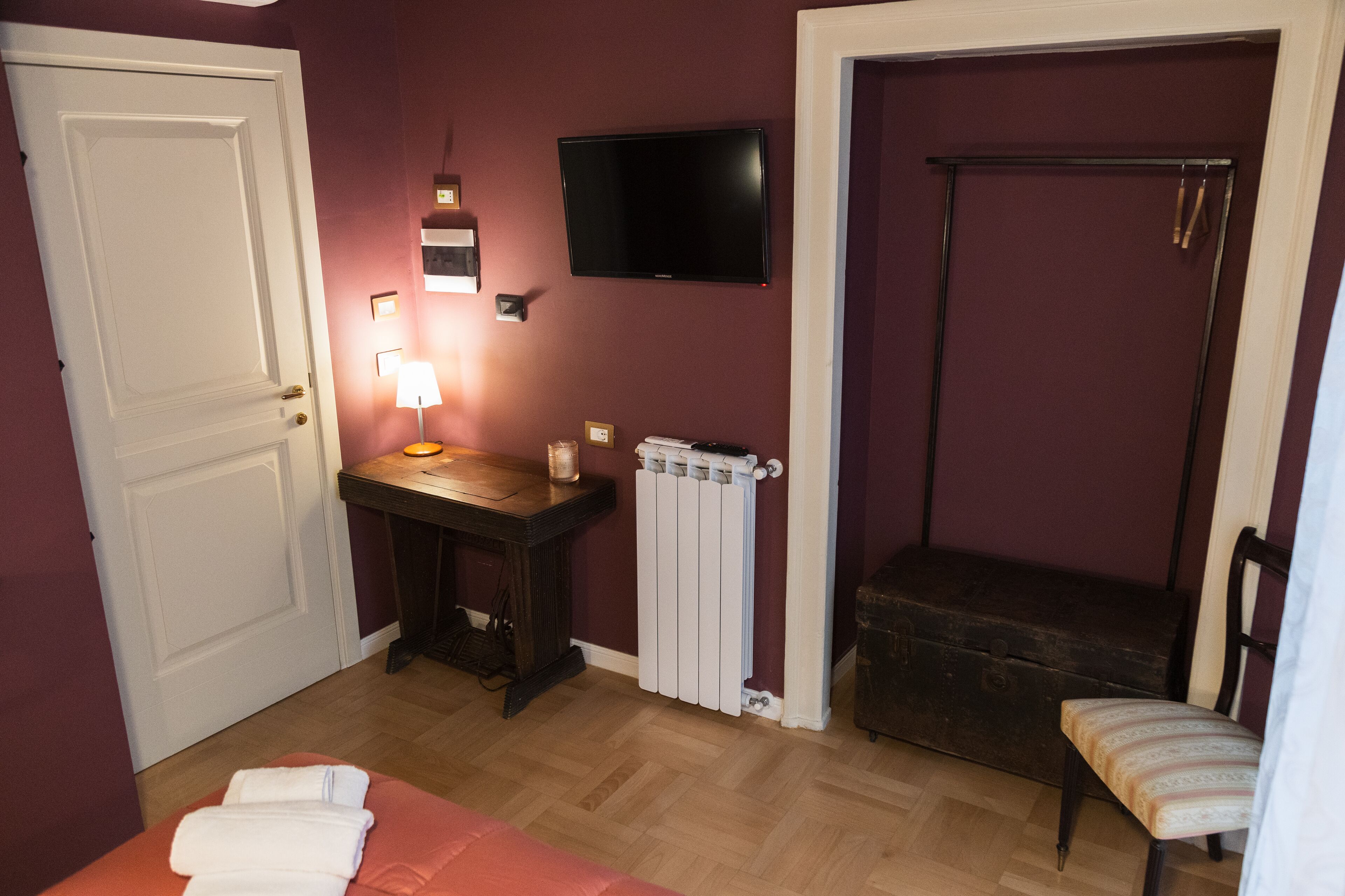 Une pièce comprenant un lit, un bureau avec une lampe, un radiateur, une télévision et une chaise.
