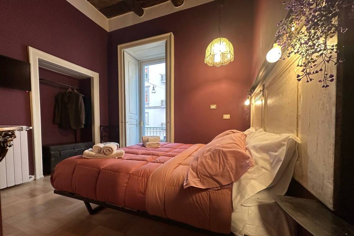 Un dormitorio con una cama grande, una mesita de noche, un espejo y una lámpara colgante.
