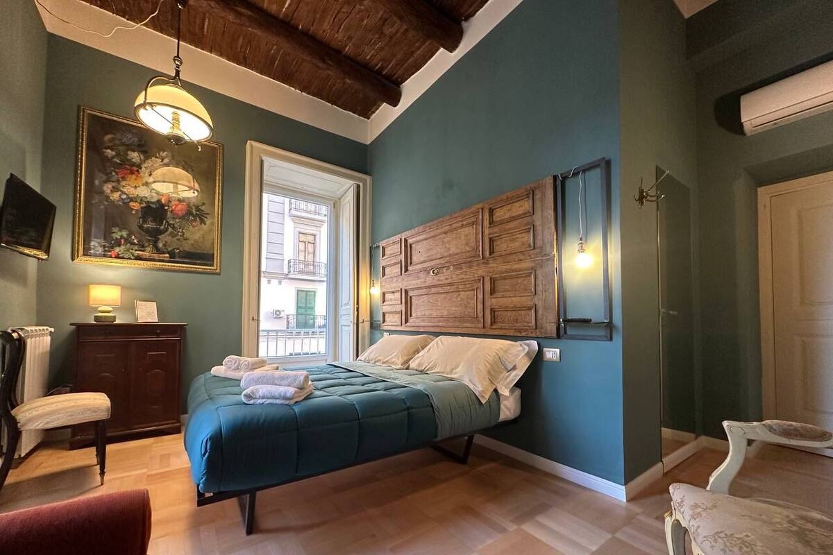 Un dormitorio con cama, cómoda, silla y un cuadro en la pared.