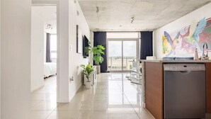 A modern kitchen with a dishwasher, a potted plant, and a view to the balcony.