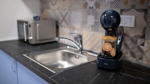 Una cocina con cafetera, tostadora y un tarro de granos de café sobre la encimera.