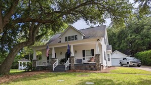 A two-story house with a porch, a flag, and a truck parked in front.