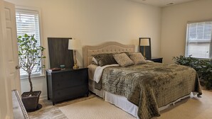 A bedroom with a bed, nightstands, a ceiling fan, a potted plant, and a window with blinds.