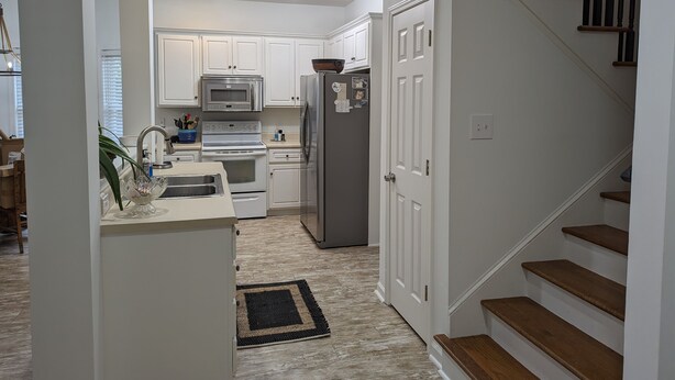 A modern kitchen with white cabinets, a stainless steel refrigerator, and a microwave.