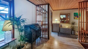 A room with a wooden floor, a black sofa, a wicker chair, a dresser, a mirror, and a potted plant. - Nice home in Romelanda with sauna (Romelanda)