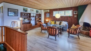 A cozy living room with wooden flooring, a sofa, two armchairs, and a coffee table. There are shelves with decorative items and a window with a view. - Nice home in Romelanda with sauna (Romelanda)