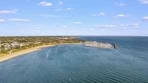 An aerial view of a coastal area with a marina, sandy beach, and residential buildings. - StayAU 2BRM Beach Family House Hampton (Hampton)