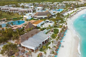 Um resort com vários edifícios, uma praia e área de piscina.