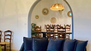 Ein Wohnzimmer mit dunkelblauem Sofa, einem Holztisch und einem Essbereich mit Holztisch und Stühlen.