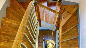 Eine Wendeltreppe aus Holz mit Metallgeländer und einer hängenden Leuchte.