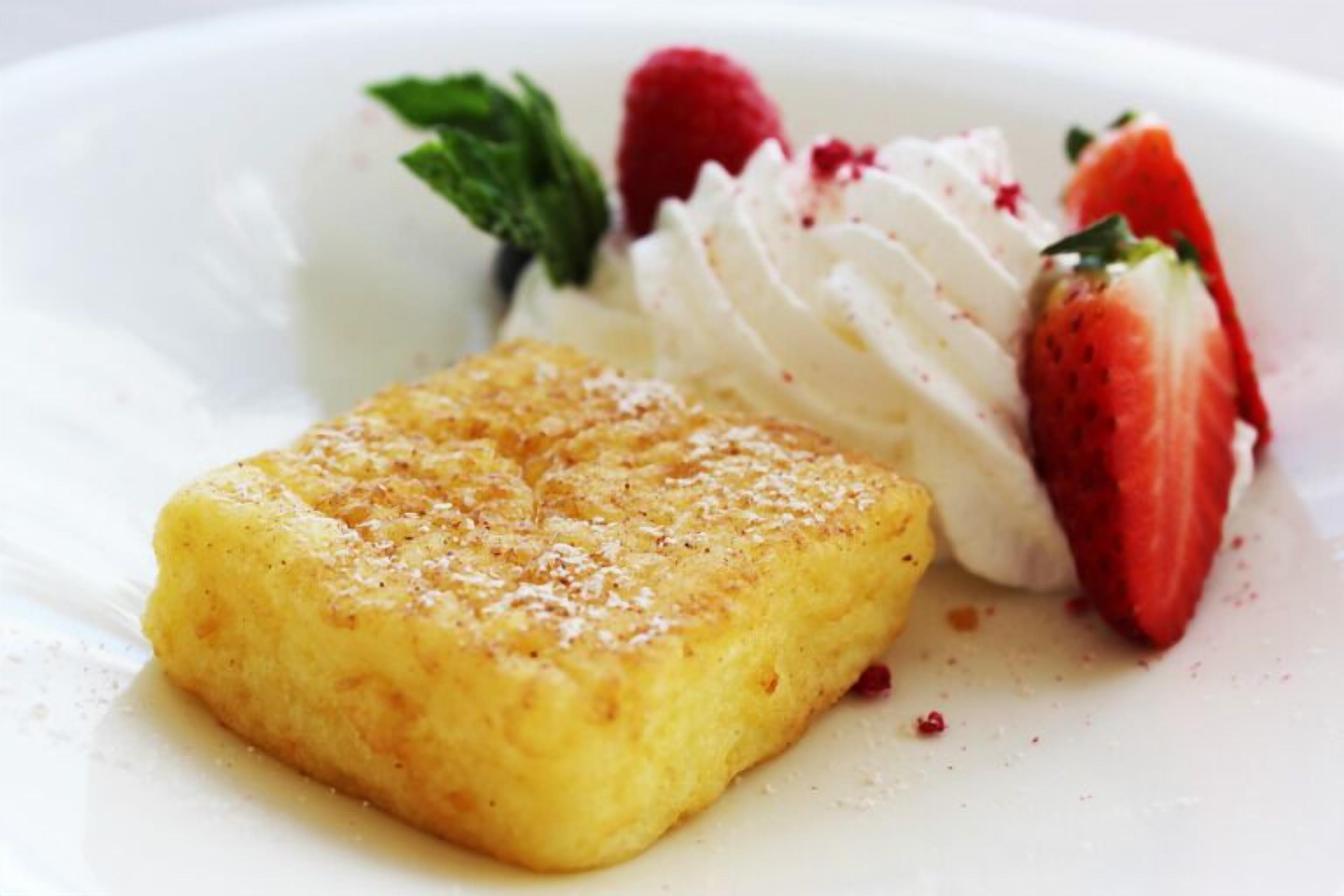 Une assiette de dessert avec un gâteau doré, de la crème fouettée et des fraises fraîches.