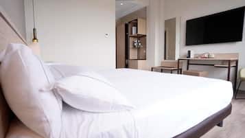 Una habitación de hotel con cama, escritorio, silla, televisor y armario.