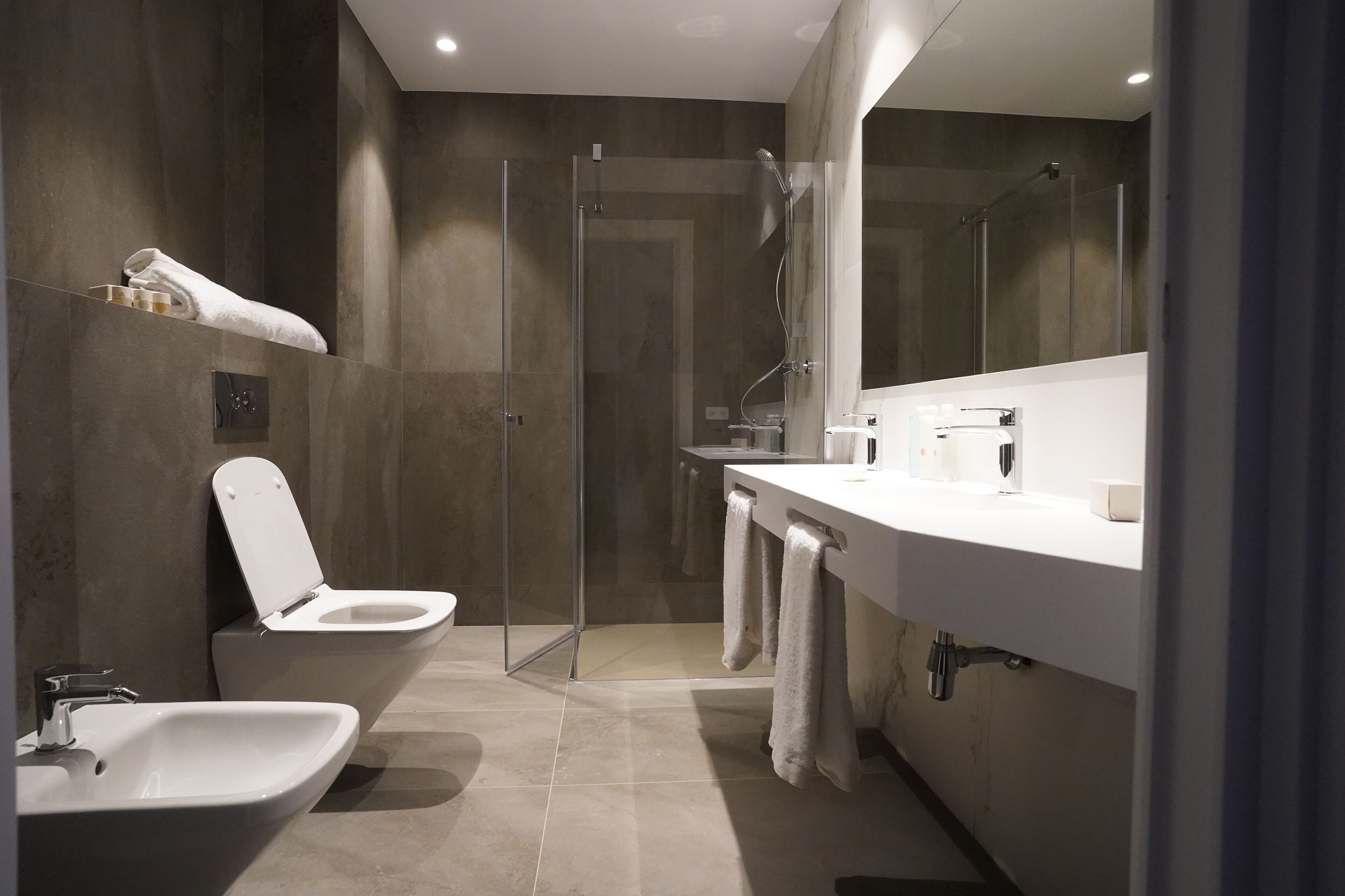 A modern bathroom with a glass-enclosed shower, a white sink, and a large mirror.