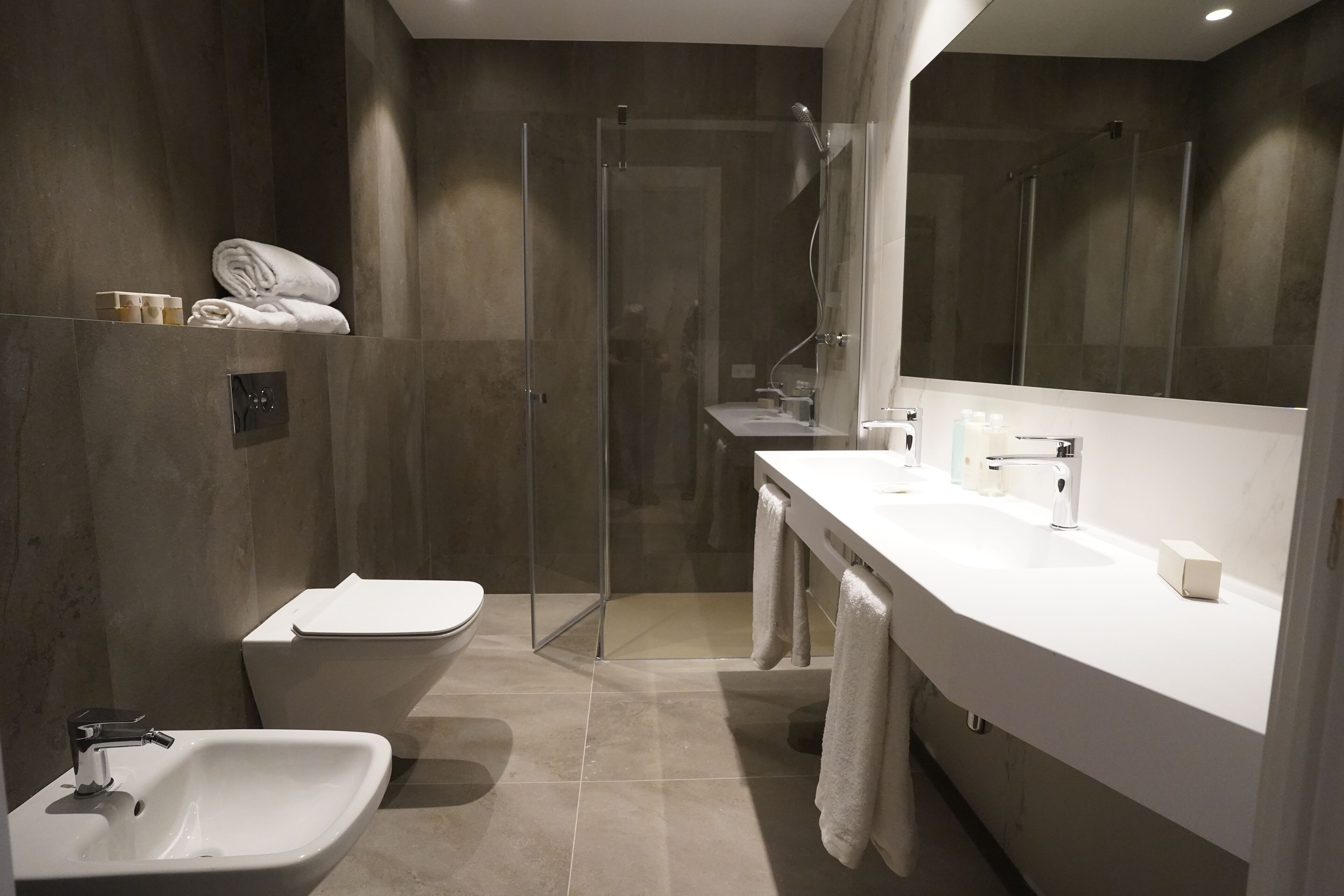 Un baño moderno con ducha de vidrio, lavamanos blanco y retrete.