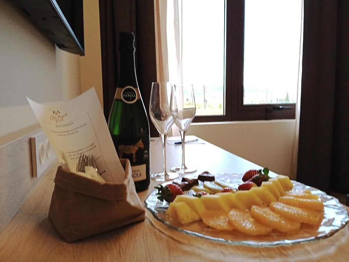 A table with a bottle of wine, two glasses, and a fruit platter.
