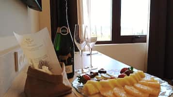 Una mesa con una botella de vino, dos copas y una bandeja de frutas.