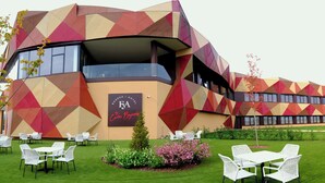 A modern hotel with geometric facade, outdoor seating, and a well-maintained lawn. - Hotel-Bodegas FyA (Navarrete)