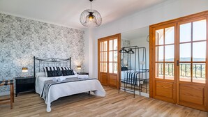 A bedroom with a bed, nightstands, a hanging chair, and a large window with a view.