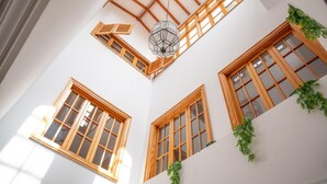 A high-ceiling room with wooden beams, a skylight, and multiple windows with wooden frames.