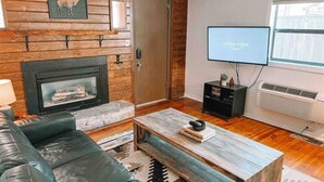 Un salon avec une cheminée, un téléviseur, un canapé et une table basse.