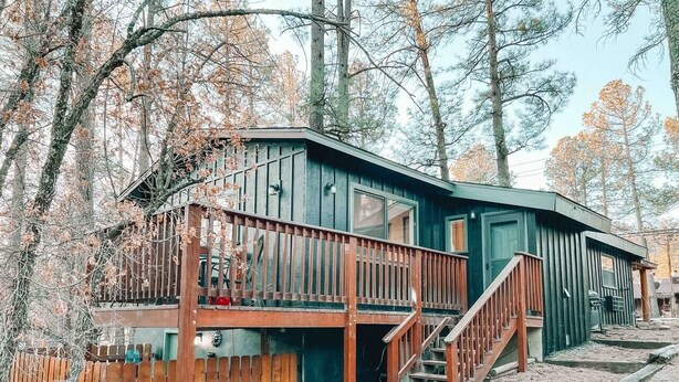 Une cabane dotée d’une terrasse en bois et d’un escalier menant à un deuxième niveau.