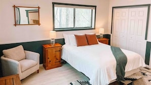 Une chambre à coucher avec un lit, des tables de chevet, une chaise, une fenêtre et une porte.