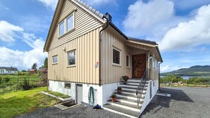 A two-story house with a sloped roof, a front door, and a small porch with steps. - Nice home in Vikebygd with house sea view (Vikebygd)