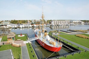 Un grand navire rouge était amarré dans une marina, à proximité d’un petit bâtiment.