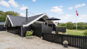 A modern house with a sloped roof, a chimney, and a black fence. - Cozy home in Vestervig with WiFi (Vestervig)