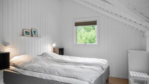 A bedroom with a bed, bedside lamps, a window with a view of greenery, and a white wardrobe. - Cozy home in Vestervig with WiFi (Vestervig)