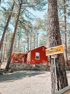 A red cabin labeled "Bears Cabin" with a stone wall and a gravel path leading to it. - Pet Friendly | Close to Nature Trails (Ruidoso)